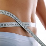 Close up of a slim waist with measuring tape.
